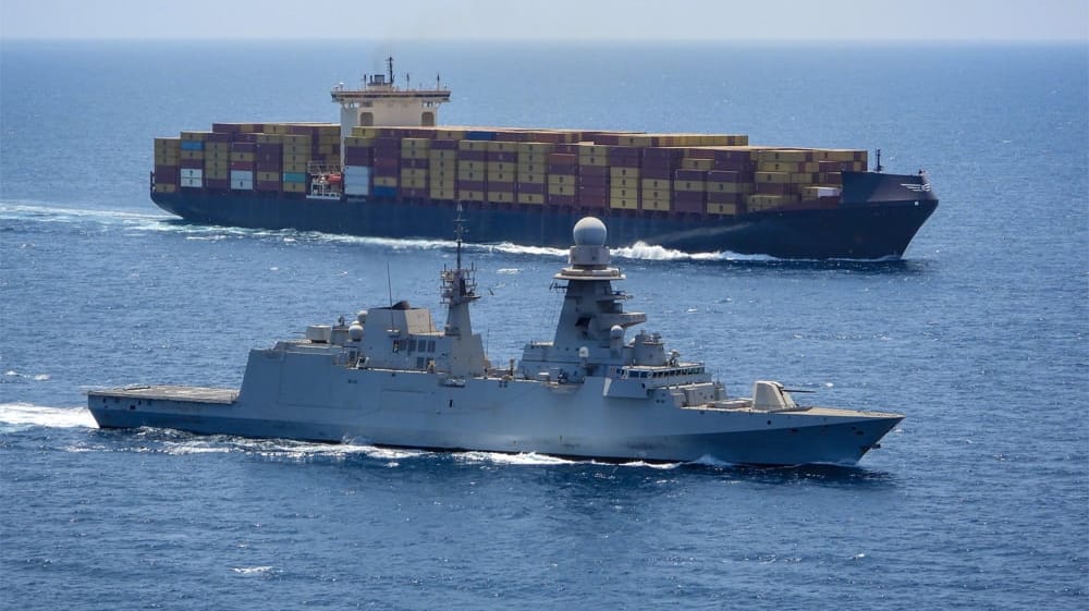 warship sailing alongside containership in the Red Sea