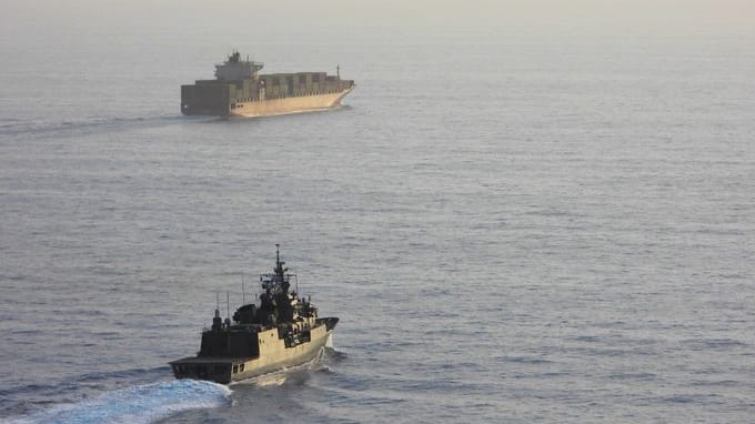 warship escorting containership in the Red Sea