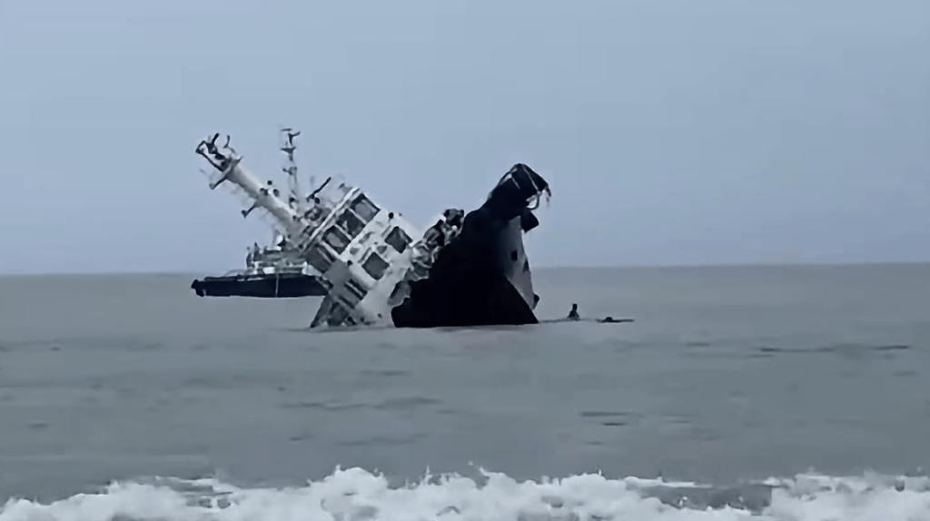 Crewmembers dive off as the tug begins to roll over (PCG)