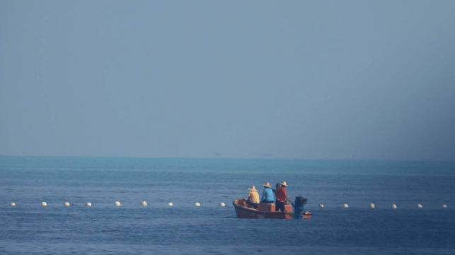 Fishermen blocked by a China Coast Guard barrier at the entrance to Scarborough Shoal (PCG file image)