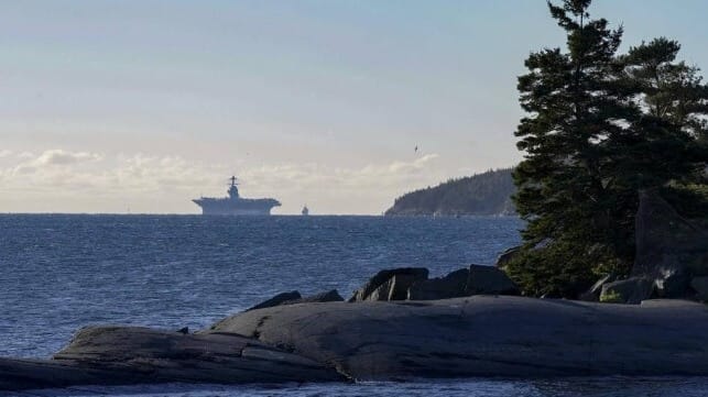 USS Ford under way off Halifax, silhouetted against a clear sky