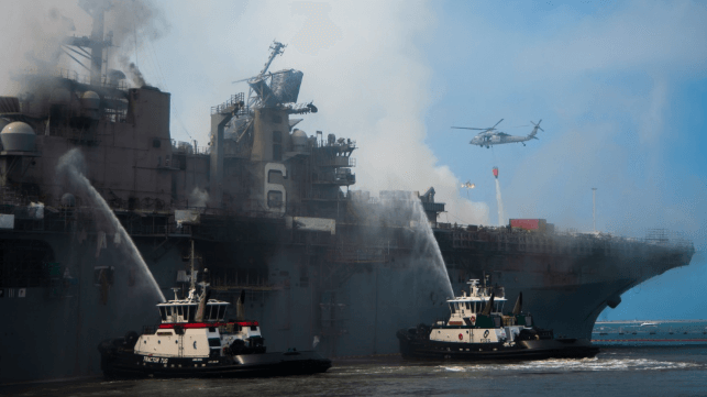 bonhomme richard on fire with tugboats attempting to cool the hull