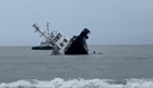 Crewmembers dive off as the tug begins to roll over (PCG)