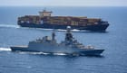 warship sailing alongside containership in the Red Sea