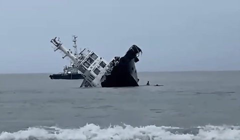 Crewmembers dive off as the tug begins to roll over (PCG)
