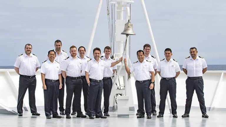 captain and officers standing at cruise ship bell