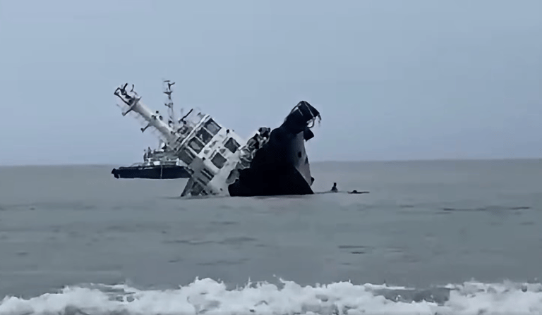 Crewmembers dive off as the tug begins to roll over (PCG)