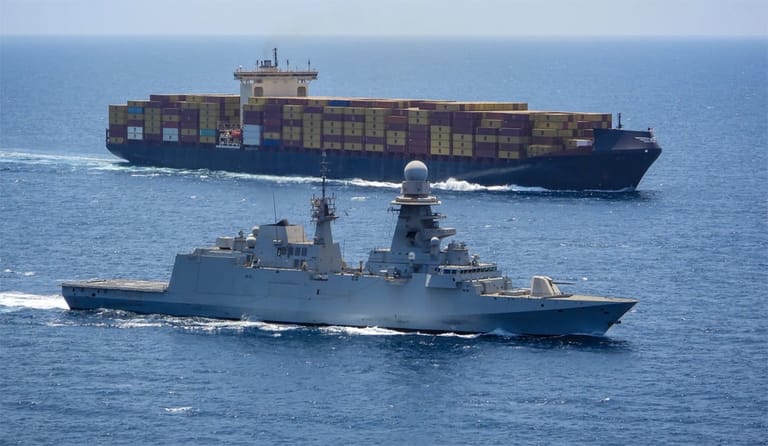 warship sailing alongside containership in the Red Sea