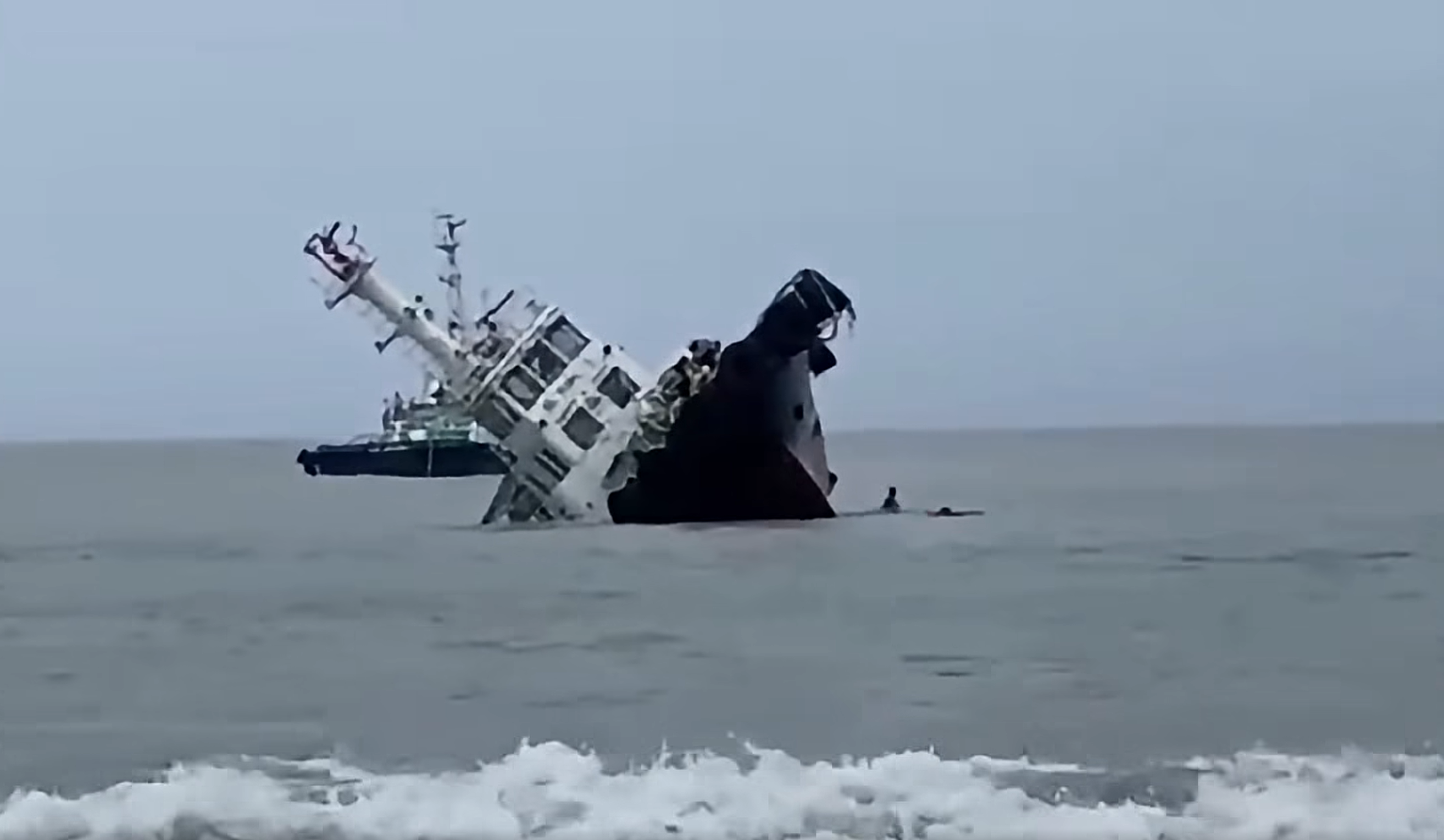 Crewmembers dive off as the tug begins to roll over (PCG)