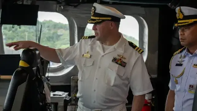 Ochs, center, provides a tour to guests during a foreign port call (USN file image)