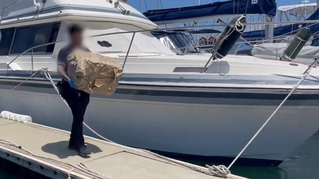 Officer carrying cocaine bundle out of boat