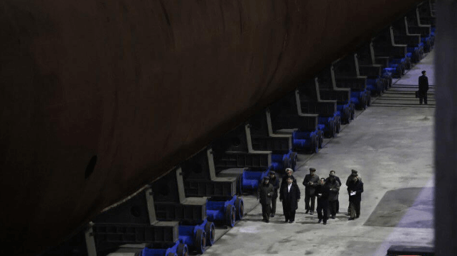 Kim Jong-un and his entourage tour a construction hall to view a claimed nuclear-powered ballistic missile submarine under construction (KCNA)