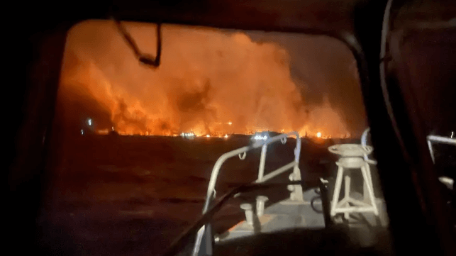 A U.S. Coast Guard rescue boat stands by to assist as fires burn on the shores of Lahaina, August 9 (USCG)