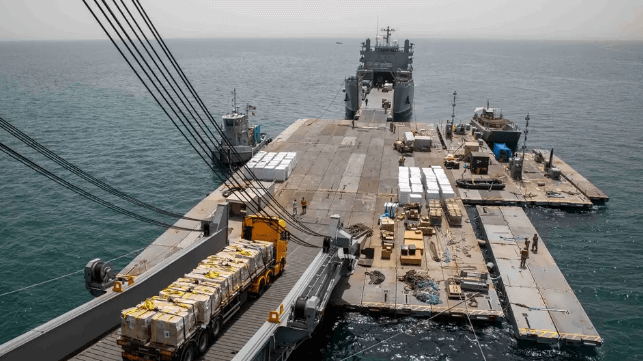 Cargo trucks carry aid for Gaza off an American sealift ship for transfer to a U.S. Army landing craft, May 20 (U.S. Army)