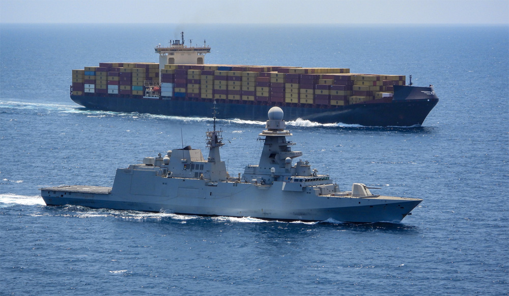 warship sailing alongside containership in the Red Sea