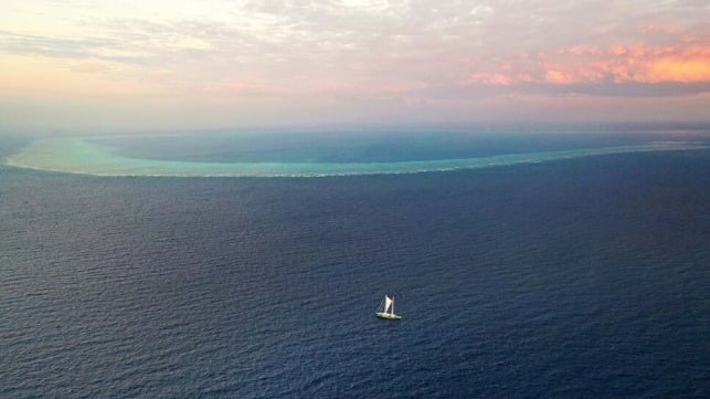 The sailboat is located on the approximate position of a proposed well site, with North Scott Reef in the background (Greenpeace)