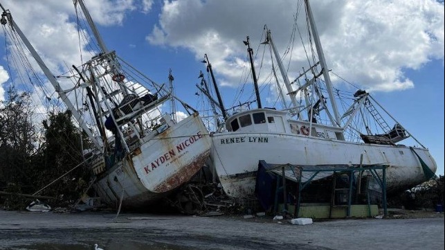 USACE image of two tipped-over fishing boats on land 