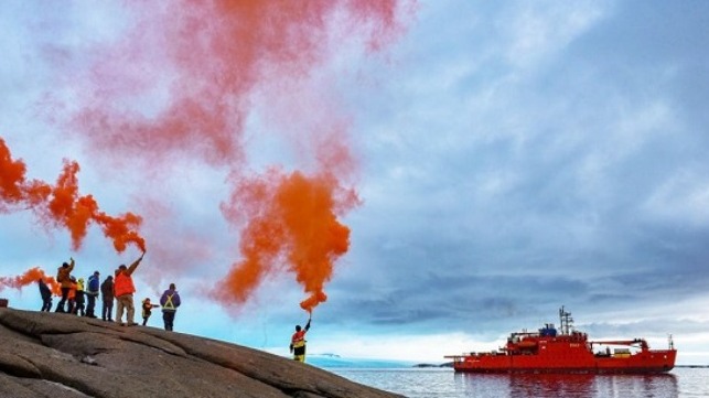 Expeditioners holding up flares to farewell the Aurora Australis, as she departs Mawson research station, 26.02.2020 (Photo: Matt Williams)