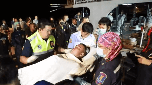 Royal Thai Navy personnel transfer an injured officer on a gurney to local EMS