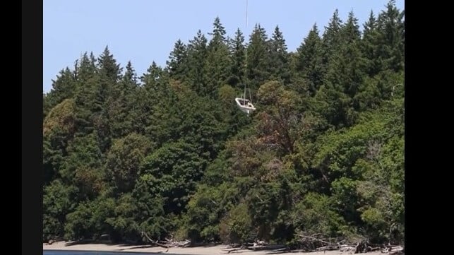 A derelict boat departs the shores of Squaxin Island via helicopter hoist (Washington DNR)