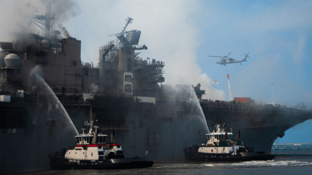bonhomme richard on fire with tugboats attempting to cool the hull
