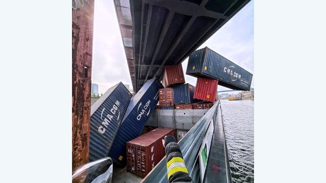 containers dangling from cargo ship stuck under railway bridge